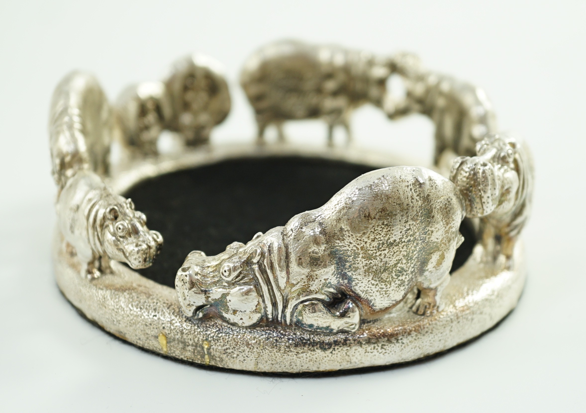 Patrick Mavros - A modern novelty silver bottle coaster, modelled as a continuous bloat of hippopotami, in various positions